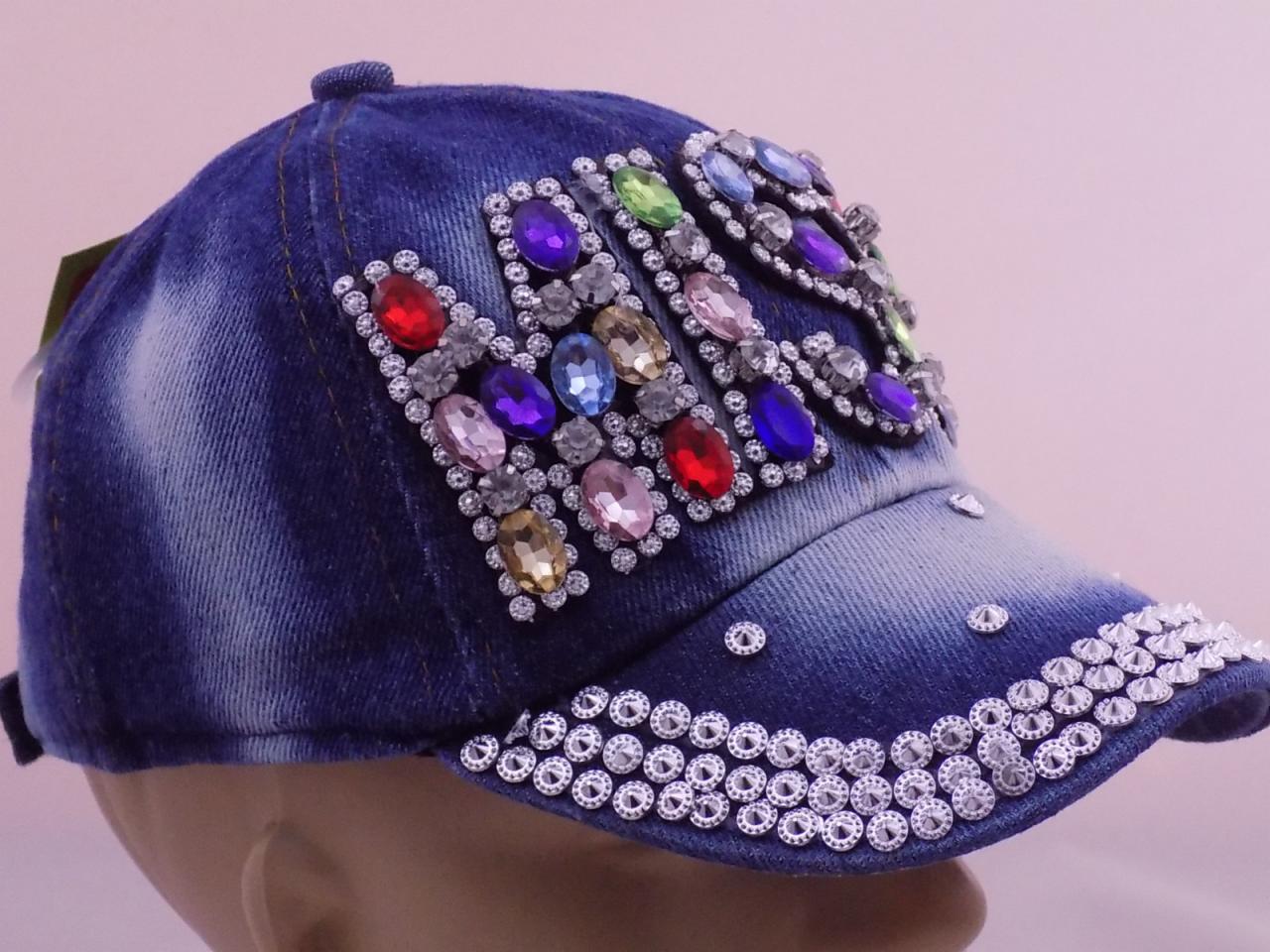 Jeansowa czapka z daszkiem ozdobiona kolorowymi i srebrnymi błyszczącymi kamieniami, ułożonymi w geometryczne wzory i obramowania.