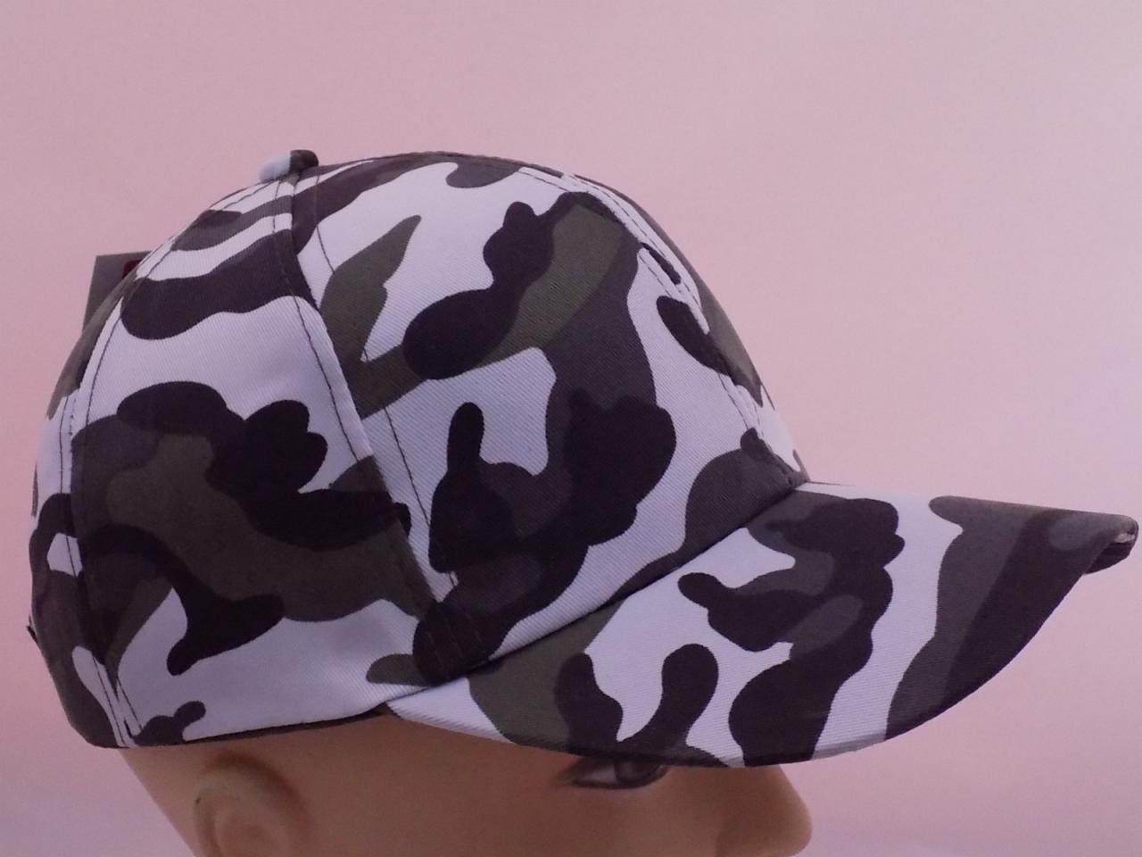 Profil kamuflażowej czapki z daszkiem na manekinie, z widoczną metką i delikatnym różowym tłem.