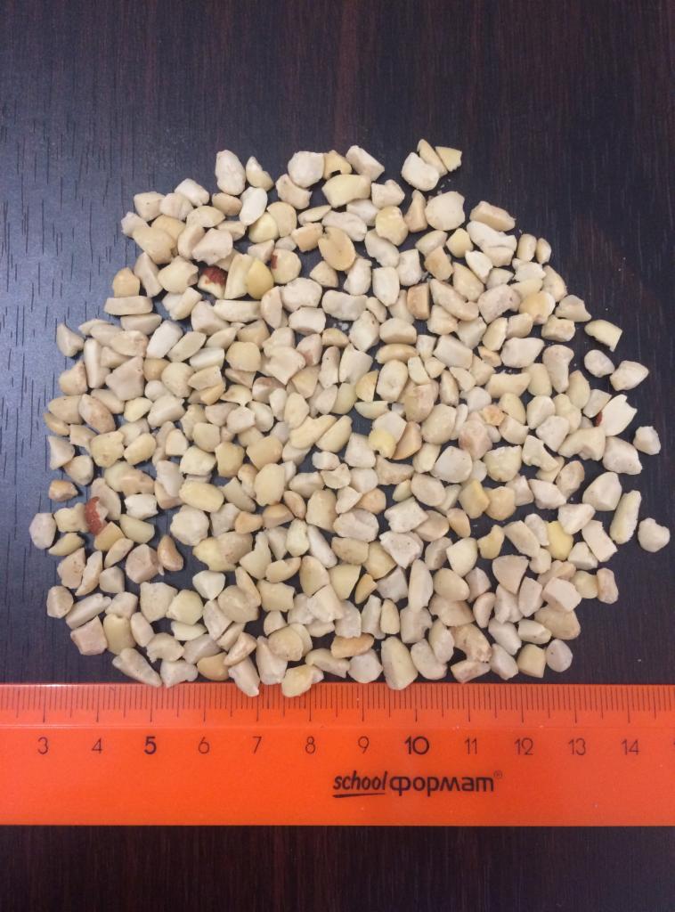 Drobno posiekane orzechy na ciemnym blacie, obok pomarańczowa linijka z podziałką w centymetrach.