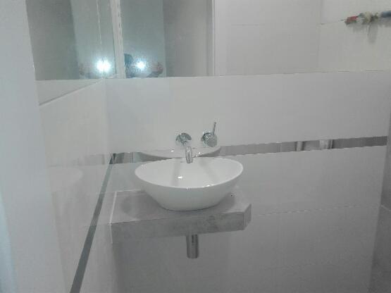 Nowoczesna, minimalistyczna łazienka w Warszawie z owalną umywalką nablatową na szarym blacie, chromowaną armaturą i dużym lustrem.