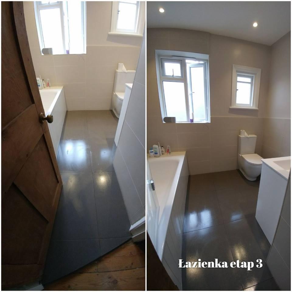 Łazienka po remoncie: widok z uchylonymi drzwiami na szare płytki podłogowe, białą wannę i toaletę, okno z otwartym skrzydłem.