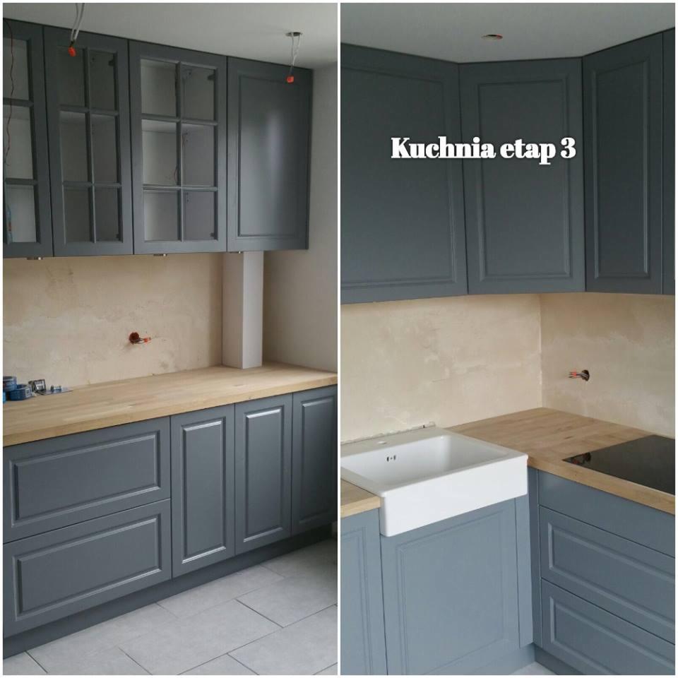 Montaż szarych mebli kuchennych w Gronowie Elbląskim, widoczny etap prac z niedokończonymi podłączeniami elektrycznymi i sanitarnymi, surowy blat drewniany i biała umywalka.