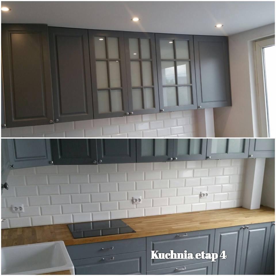 Szare szafki kuchenne, górne z przeszklonymi frontami, dolne z drewnianym blatem, białe kafelki na ścianie ułożone w cegiełkę, widoczna płyta indukcyjna.
