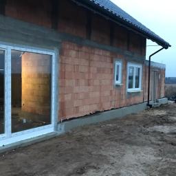 P.H.U. Para- door Łukasz Zadański - Surowy stan budynku w trakcie budowy z zamontowanymi oknami PCV o białych ramach, widoczne pustaki ceramiczne i betonowe wylewki, ziemia przed budynkiem.