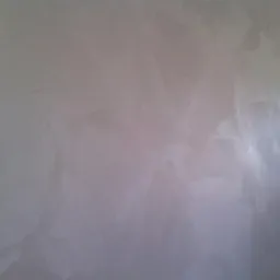 Ściana pokryta dekoracyjną, perłową farbą z wyraźną fakturą, oświetlona z prawej strony, tworząca subtelne refleksy świetlne.