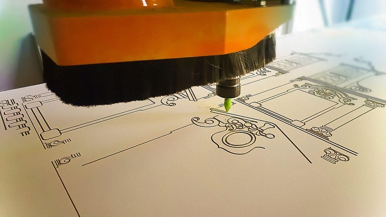 Frezarka CNC wycina precyzyjny wzór architektoniczny na jasnej płycie, zbliżenie na głowicę i detale ornamentu.