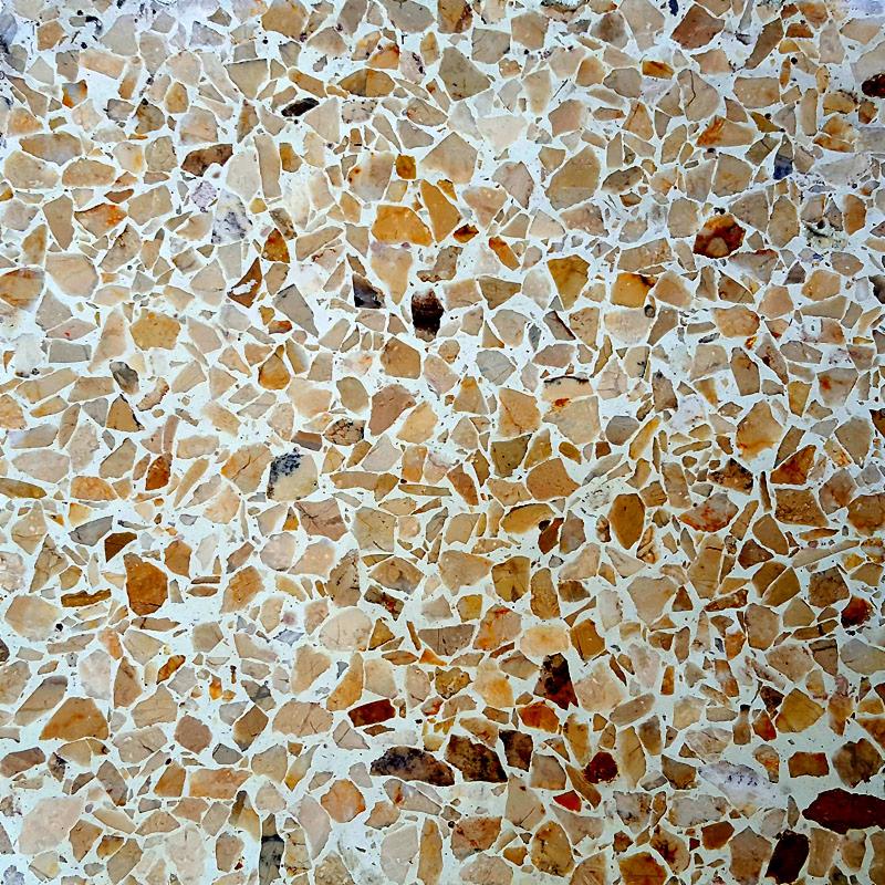 Polerowana posadzka lastryko z drobnymi, nieregularnymi kamyczkami w odcieniach beżu i brązu, osadzonymi w jasnym spoiwie.