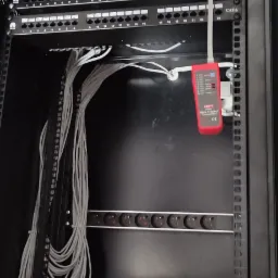 Szafa serwerowa z patch panelem CAT6, okablowaniem strukturalnym i testerem kabli Uni-T, narzędzia na spodzie szafy.