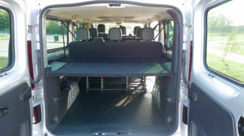 Wnętrze srebrnego busa z zamontowanymi siedzeniami i dodatkową półką transportową, widok z otwartych tylnych drzwi, pojazd z Zamościa.