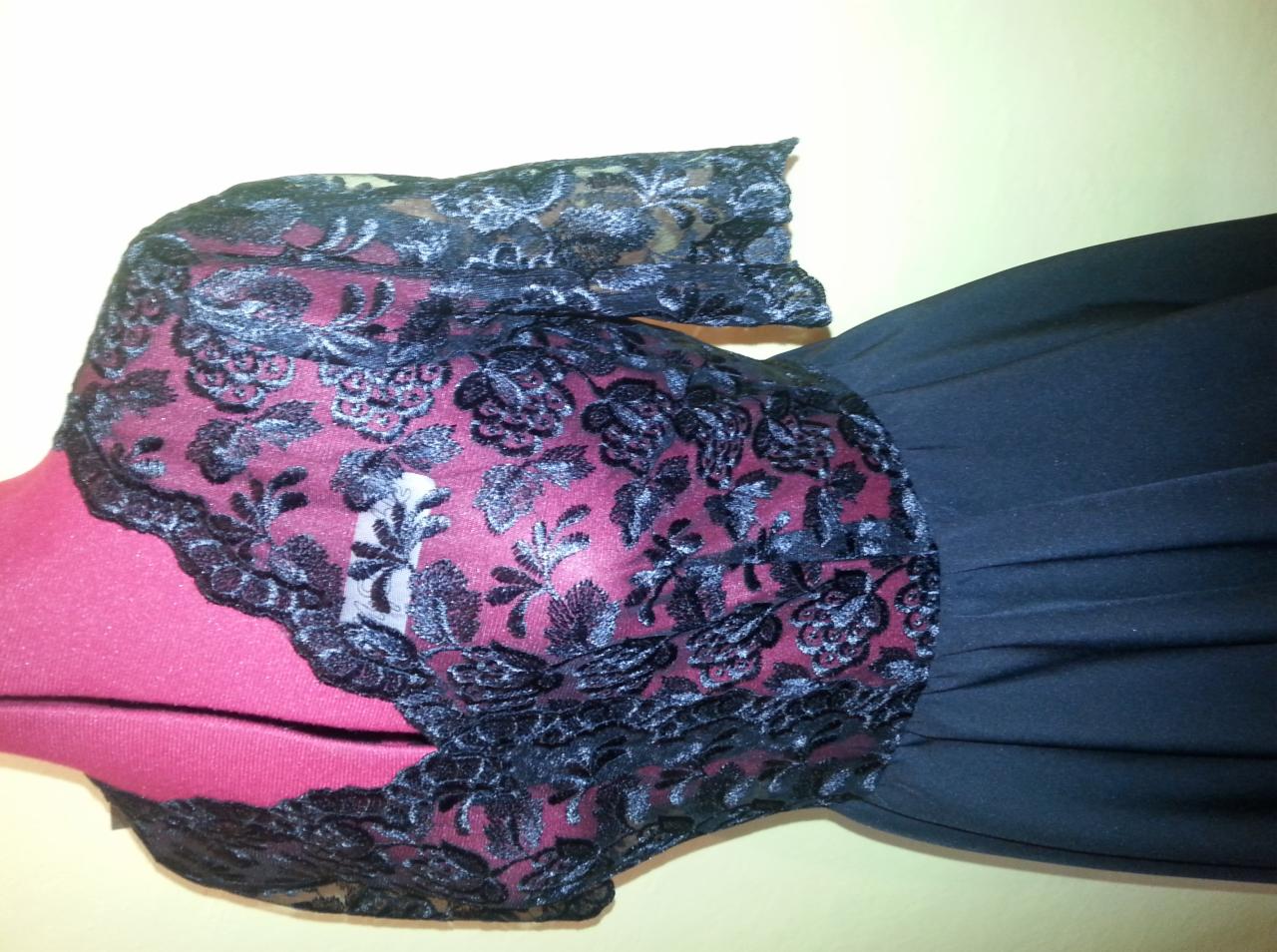 Fragment sukienki z czarną koronką na czerwonym manekinie, z ciemnogranatowym dołem.