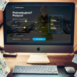 Ekran komputera z formularzem online do wnioskowania o pożyczkę, otoczony plikami banknotów o nominałach 50 i 100 zł, widoczne biurko z klawiaturą i myszką.