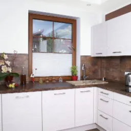 Kuchnia w Czańcu z drewnianym oknem i plisowaną osłoną okienną w kolorze białym, zapewniającą prywatność i kontrolę światła.