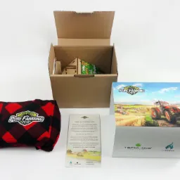 Prezentacja zestawu promocyjnego gry Pure Farming 2018: pudełko z grafiką, koszula flanelowa w kratę, kartonowe opakowanie z zawartością i ulotka informacyjna na białym tle.