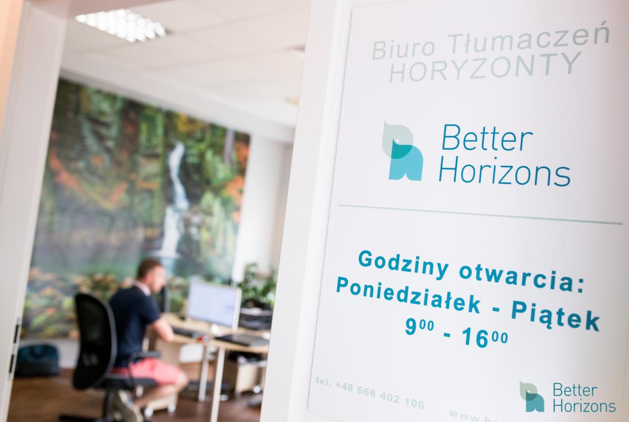 Tablica informacyjna z logo i godzinami otwarcia biura tłumaczeń 'Better Horizons', w tle pracownik przy biurku i fototapeta z motywem wodospadu.