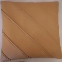 Beżowa, kwadratowa poduszka dekoracyjna ze skośnymi przeszyciami na białym tle.