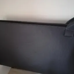 Szara torba z ekoskóry z uchwytami, widoczna z boku, z delikatnym przeszyciem na krawędzi i ciemnym wykończeniem górnej krawędzi.