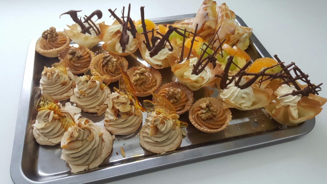 Srebrna taca z różnorodnymi mini deserami: bezy z kremem i migdałami, babeczki z orzechami włoskimi i karmelowym nadzieniem, kruche koszyczki z kremem i dekoracją z gorzkiej czekolady...