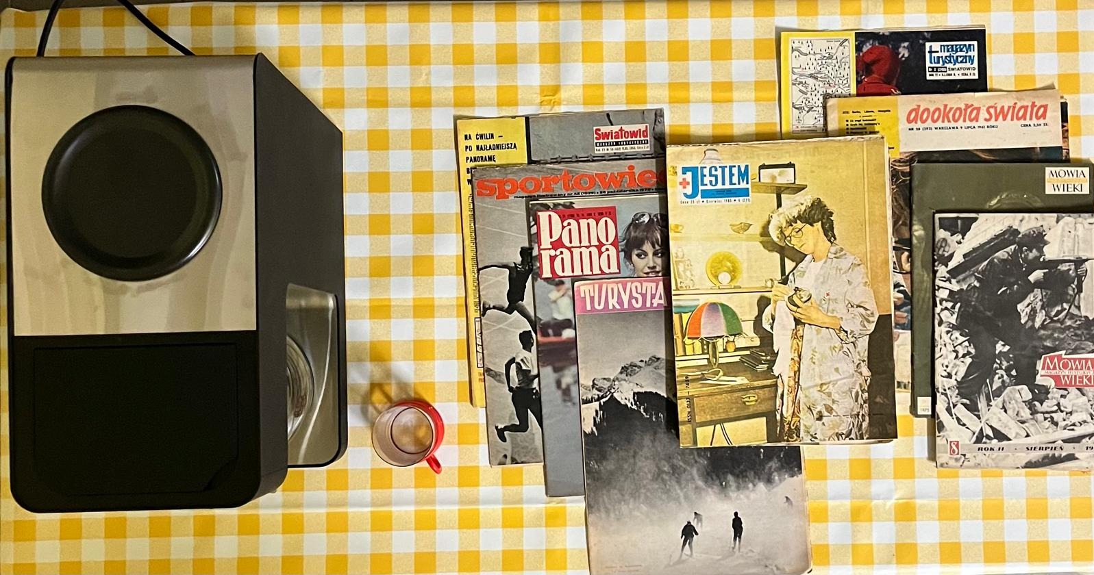 Kawa z ekspresu i sterta retro magazynów na żółto-białym obrusie w kratkę. Widoczne tytuły: Światowid, Panorama Turysty, Jestem, Mówią Wieki, Dookoła Świata.