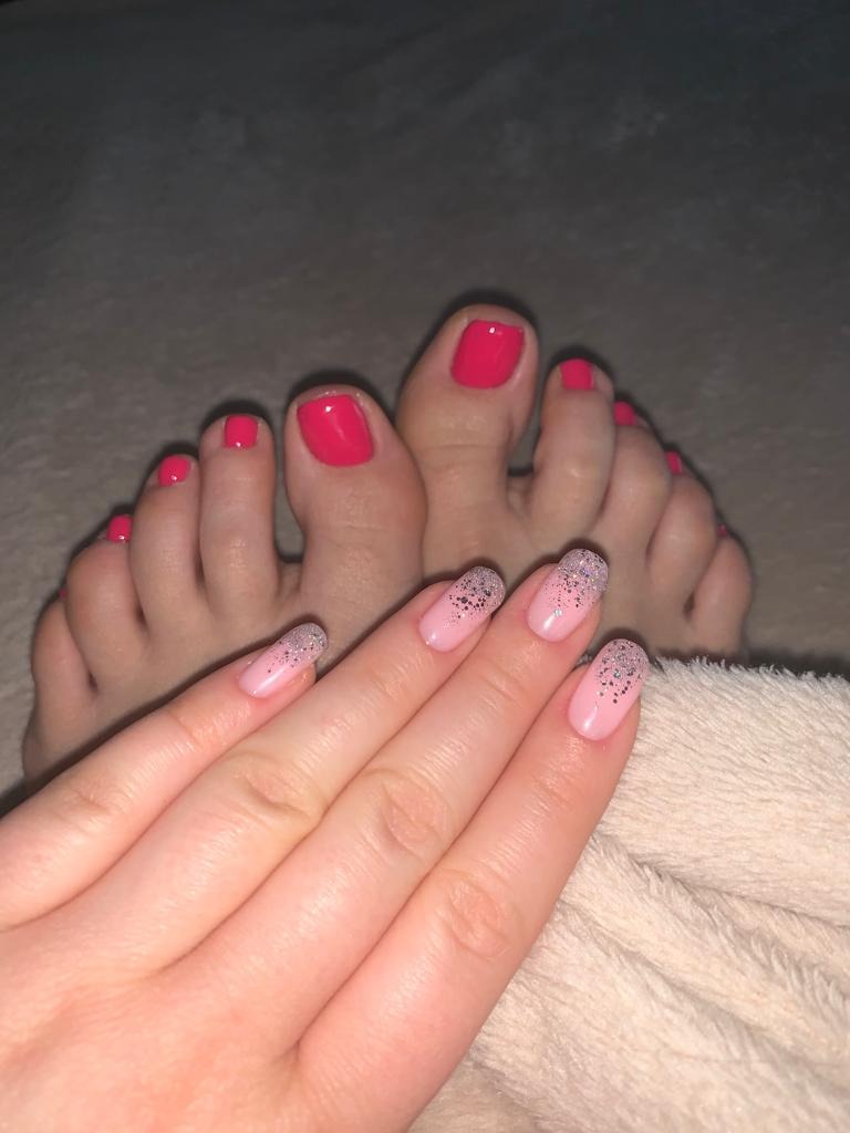 Ręka z delikatnym różowym manicure z brokatowym ombre i stopy z jaskrawym różowym pedicure na tle miękkiego koca.