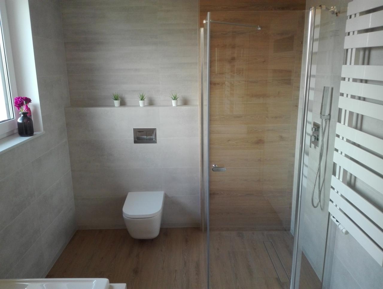 Nowoczesna łazienka z kabiną prysznicową typu walk-in, podwieszaną toaletą i dekoracyjnymi roślinami w doniczkach na półce.