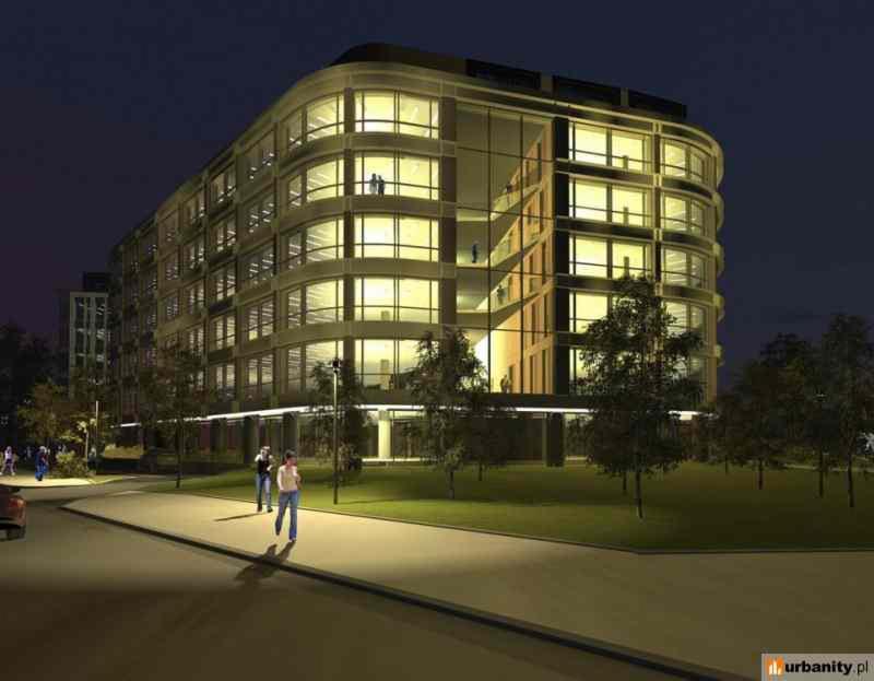 Nowoczesny budynek biurowy z zaokrąglonymi narożnikami, oświetlony nocą, z widocznymi osobami wewnątrz, otoczony zielenią i chodnikiem.