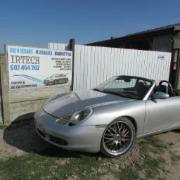 Srebrny Porsche Boxster kabriolet zaparkowany przed warsztatem samochodowym z szyldem reklamowym 'IRTECH Auto Serwis Mechanika Diagnostyka' oferującym naprawy silników, blacharskie, lakiernicze...