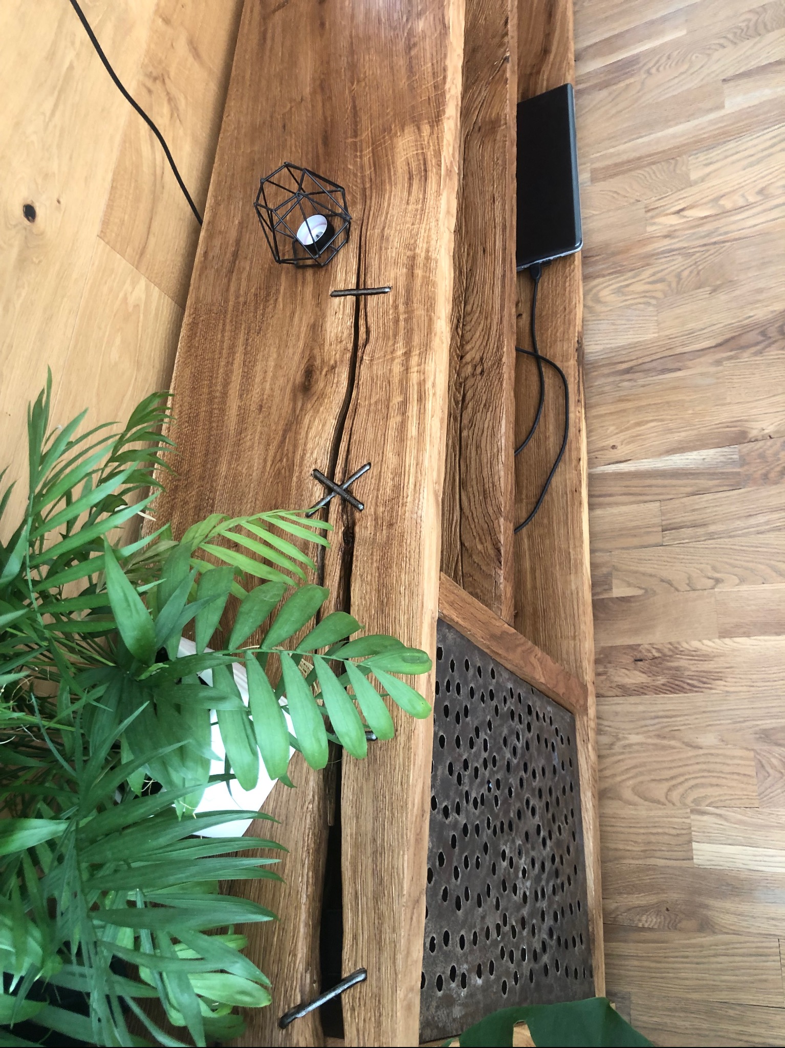 Rustykalna konsola z litego drewna dębowego z widocznymi pęknięciami, metalowymi wstawkami i ażurowym frontem, uzupełniona rośliną doniczkową i dekoracjami.