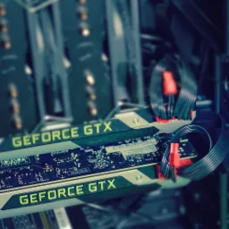 Dwie karty graficzne GeForce GTX zainstalowane wewnątrz obudowy komputera, z widocznymi kablami zasilającymi i elementami płyty głównej w tle.