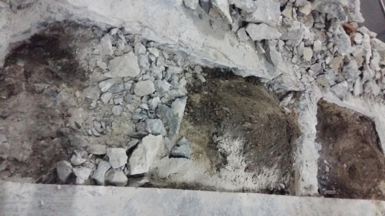 Fragment podłogi w trakcie skuwania w Warszawie, widoczne gruz, ziemia i odsłonięte fundamenty.