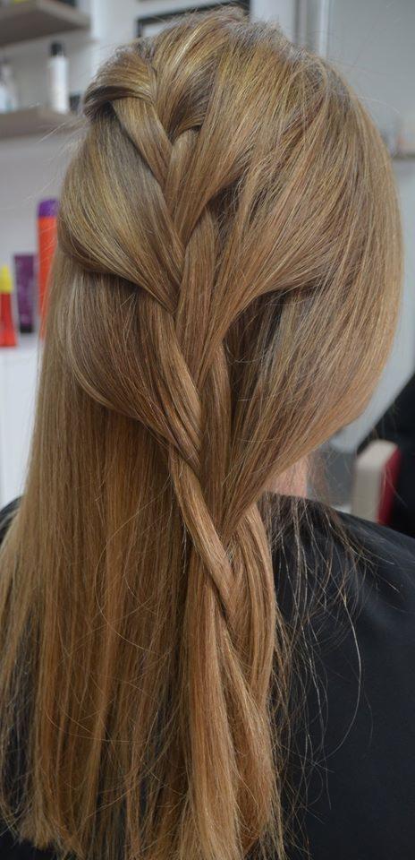 Blond włosy z zaplecionym warkoczem typu kłos, widok z tyłu, w tle półki z kosmetykami.