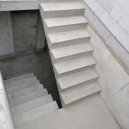 Mariusz Łapot budownictwo - Surowe, betonowe schody wewnętrzne w trakcie budowy, widok z góry, z widocznymi bloczkami z betonu komórkowego po bokach.