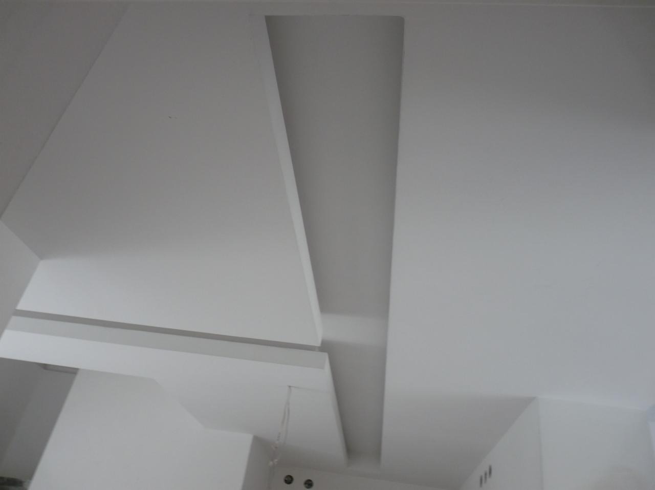 Biały sufit z elementami dekoracyjnymi z płyt, widoczne przewody i punkty oświetleniowe