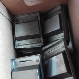 WR Rafał Wisiński - Metalowe obudowy z otworami na śruby, ułożone w kartonowym pudle, widoczne ślady montażu.