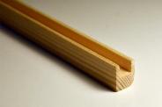 Profilowana listwa z jasnego drewna iglastego, widoczny przekrój w kształcie litery U, oświetlenie naturalne, lekki cień.
