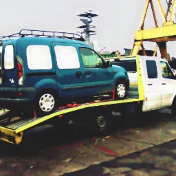 Niebieski samochód dostawczy Renault Kangoo zabezpieczony pasami na żółtej platformie lawety w otoczeniu przemysłowym z dźwigiem w tle.