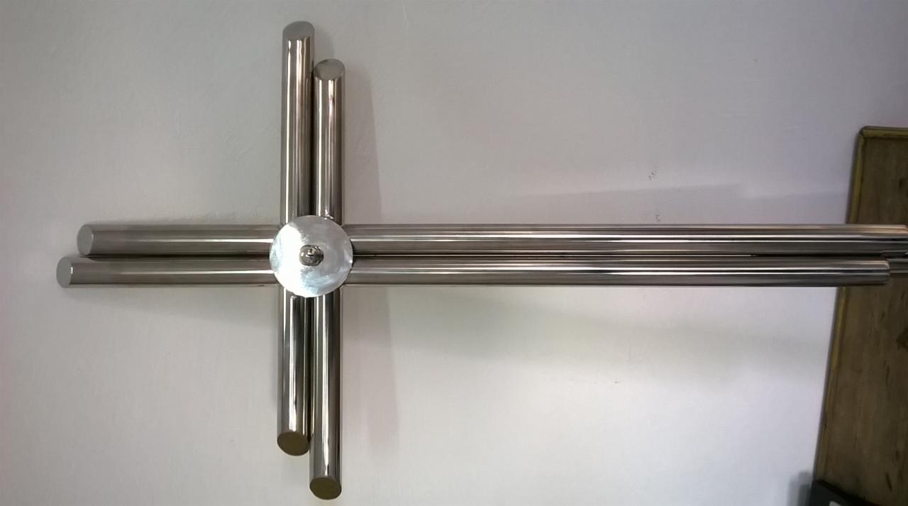 Nietypowe mocowanie poręczy ze stali nierdzewnej, rury ułożone w kształt krzyża, widoczne mocowanie do ściany za pomocą okrągłej płytki.