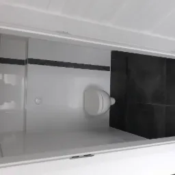 Wykończona łazienka z białą armaturą, czarnymi płytkami i listwą dekoracyjną, widok z perspektywy szafki.