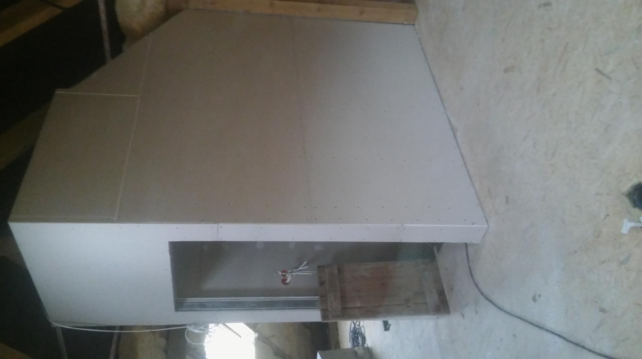 Wykończone poddasze z płyt karton gips, widoczna wnęka z wystającymi przewodami elektrycznymi i fragment drewnianej konstrukcji w surowym stanie.