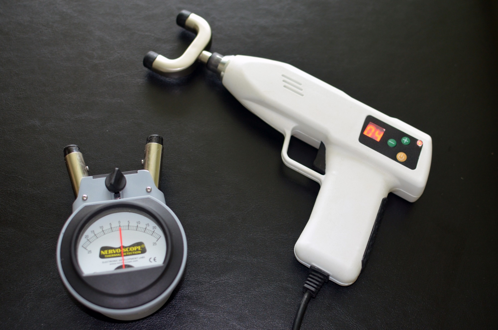 Nervoscope Thermal Detection devices: analog indicator and digital gun-shaped instrument with probes, used in chiropractic for spinal analysis.