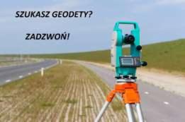 Profesjonalny niwelator optyczny koloru turkusowo-pomarańczowego ustawiony na polu z widoczną drogą w tle i hasłem 'Szukasz geodety? Zadzwoń!'