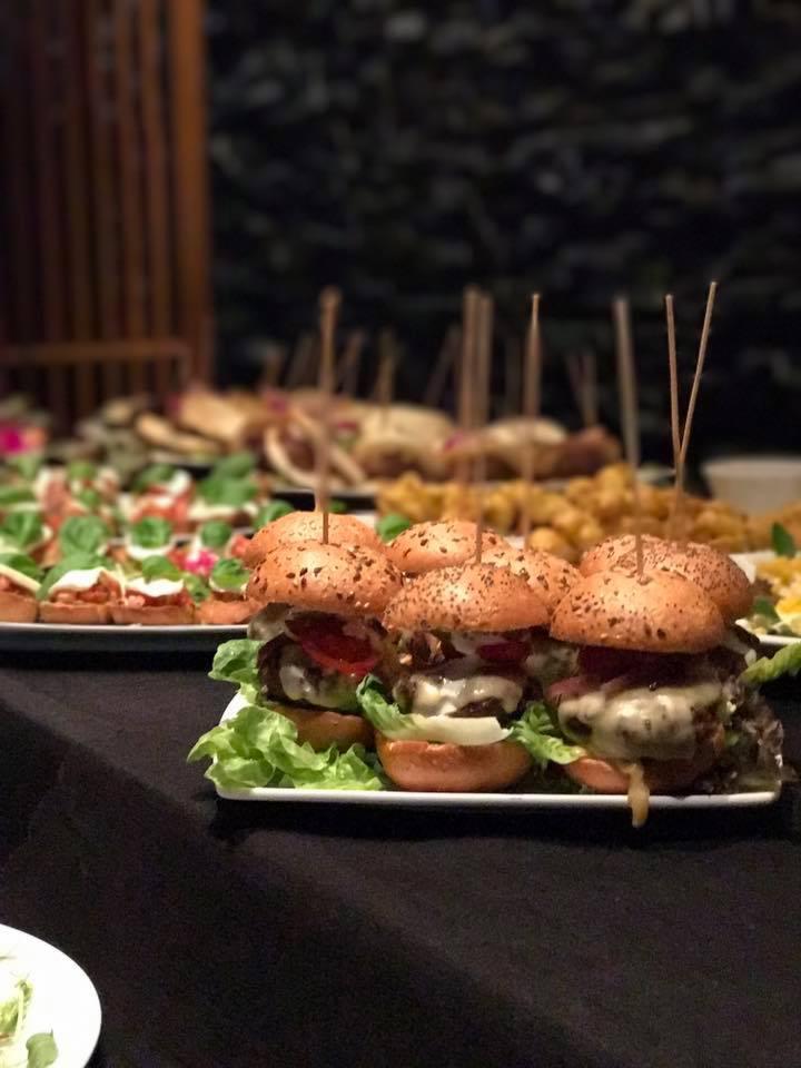 Mini burgery z warzywami i serem, podane na białym talerzu, część bufetu z przekąskami na ciemnym stole