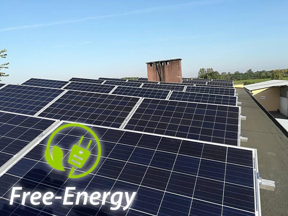 Rząd paneli słonecznych na dachu z kominem w tle, z nałożonym logo 'Free-Energy' z zielonym symbolem wtyczki.