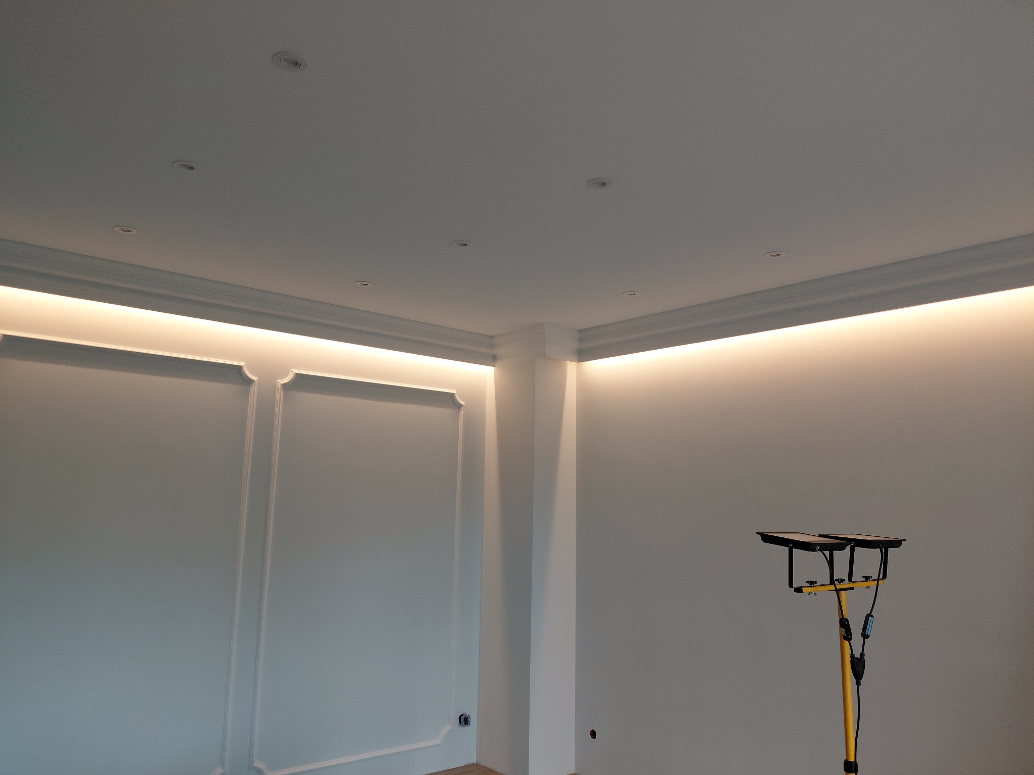 Wykończone wnętrze z dekoracyjną sztukaterią ścienną i oświetleniem LED podsufitowym. Widoczna lampa robocza. Świeżo po remoncie, gotowe do użytku.