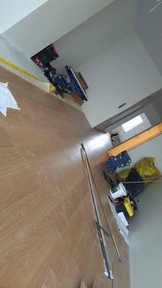 Układanie parkietu w jodełkę w jasnym pomieszczeniu, widoczne narzędzia pracy, klej i paczki z panelami