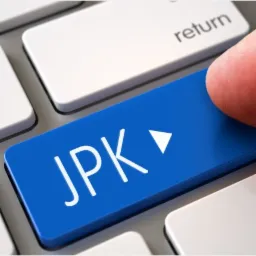 Palec naciska niebieski klawisz z napisem JPK na klawiaturze komputera.