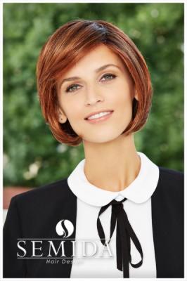 Portret kobiety z rudą peruką typu bob, ubrana w czarną marynarkę i białą bluzkę z kokardą, na tle zieleni, z widocznym logo firmy Semida Hair Design.