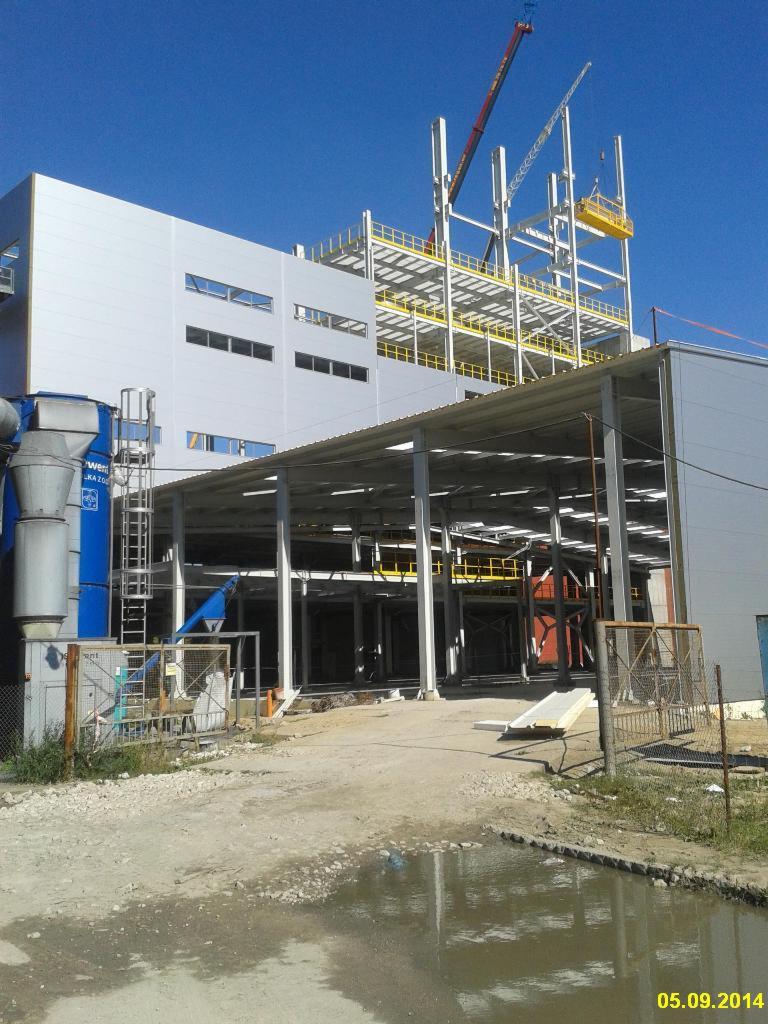 Budowa hali z widoczną konstrukcją szkieletową, dźwigiem w tle i fragmentem elewacji z płyt warstwowych, z datą 05.09.2014 w prawym dolnym rogu.