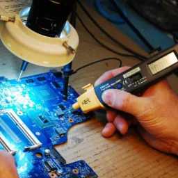 Diagnostyka płyty głównej laptopa w Opolu przy użyciu multimetru i lampy inspekcyjnej podczas serwisu.