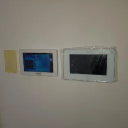 Dwa panele sterowania systemem alarmowym zamontowane na ścianie, jeden marki Satel z widocznym ekranem dotykowym, drugi marki Dahua, jeszcze w folii ochronnej.