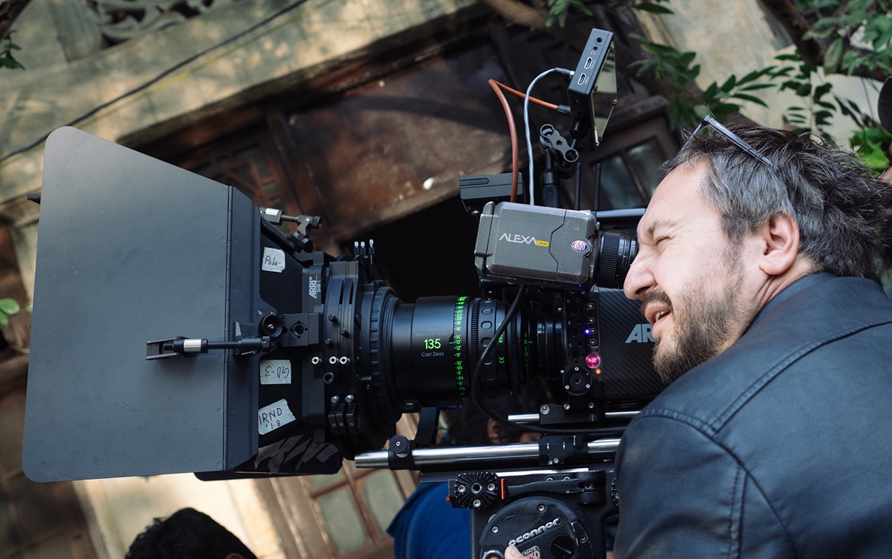 Operator filmowy z kamerą Arri Alexa i obiektywem Carl Zeiss 135mm na planie filmowym z budynkiem w tle.